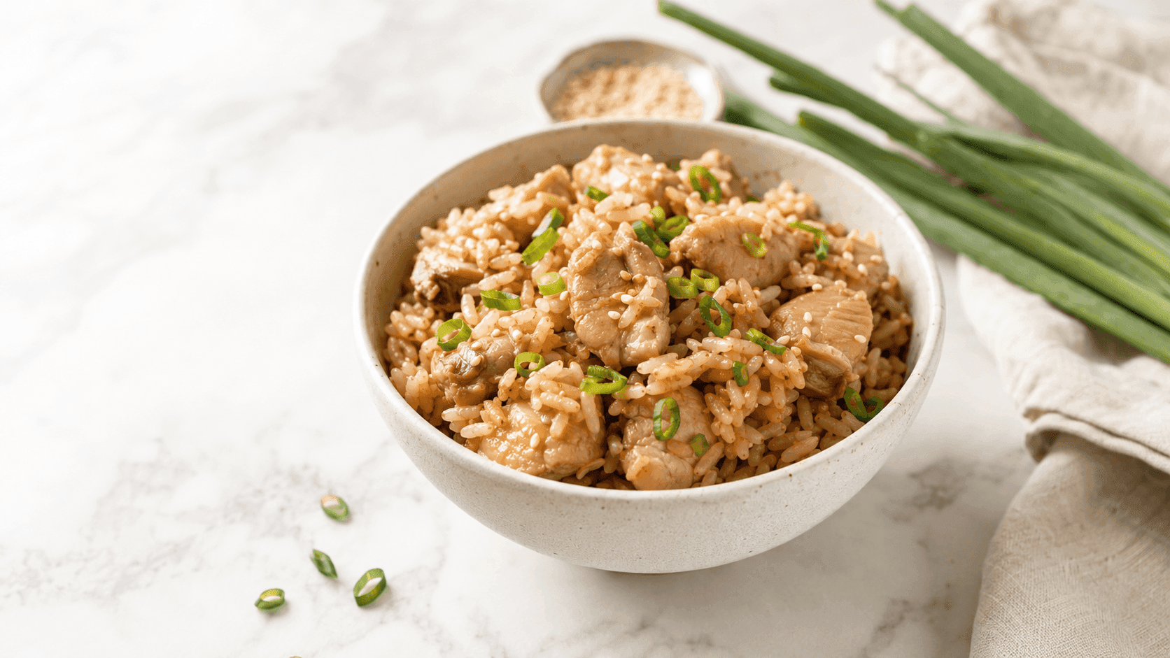 Easy rice cooker chicken and rice topped with green onions in a bowl